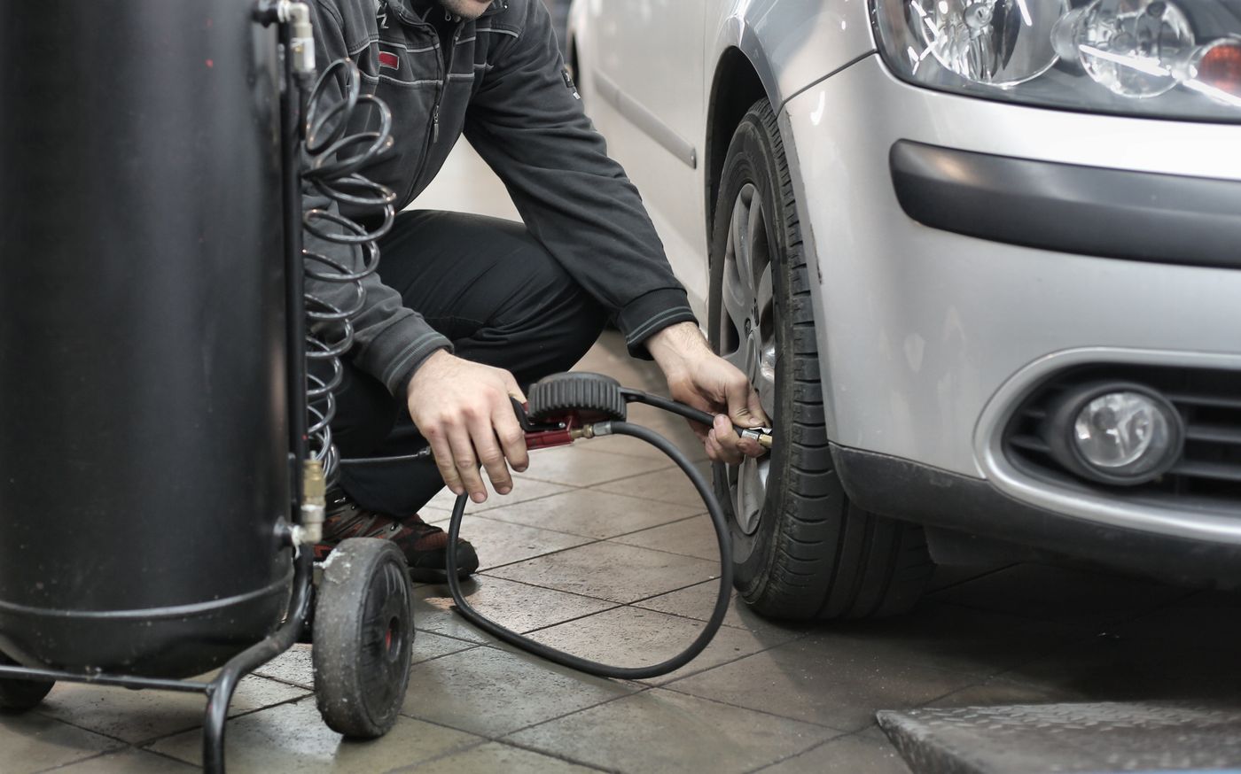 Mains contrôlant la pression d’un pneu avec un manomètre, visage hors cadre